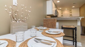 A dining area with a table set for four, clear glass glasses, and a decorative branch on the wall. - Ocean View Escape Studio Condo (Rehoboth Beach)