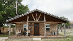 Un rustico chalet in legno con veranda, una porta d'ingresso e due finestre.