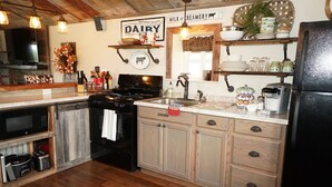 Una cucina con piano cottura, forno, microonde e diversi oggetti da cucina sul bancone.