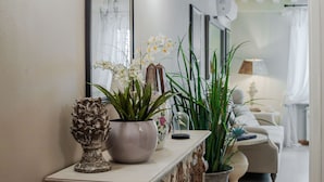En stue med et sofabord, en potteplante og en vase med blomster.