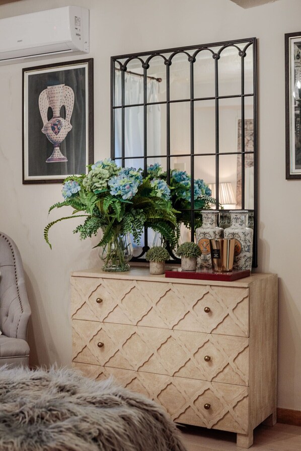 A room with a wooden cabinet, a mirror, and a framed picture on the wall.