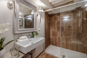 A modern bathroom with a glass-enclosed shower, a white sink, and a large mirror. - Luxury 1 Bedroom Apartment inside the Walls of Lucca (Lucca)