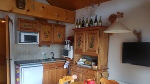 Eine Küche mit Holzausstattung, einer Mikrowelle, einem Geschirrspüler und einem Esstisch mit einer Karaffe.