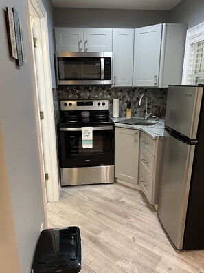 A modern kitchen with white cabinets, a stainless steel stove, a microwave, and a refrigerator.