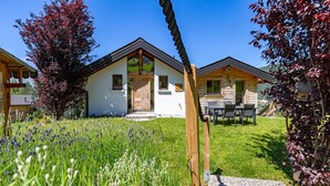 A row of wooden cabins with a grassy yard and a stone pathway leading to the entrance. - Chalet Lupin - Four Bedroom Chalet, Sleeps 11 (Riddes)