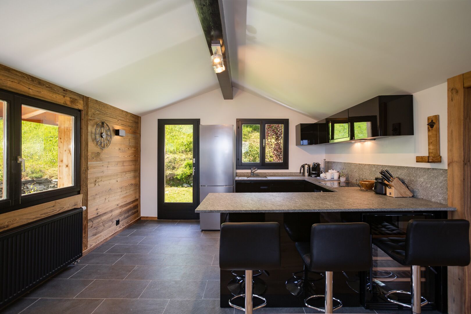 Een moderne keuken met een centraal eiland, barstoelen, een koelkast en een spoelbak.