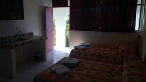 Une chambre avec deux lits, une petite kitchenette et un balcon avec des rideaux.