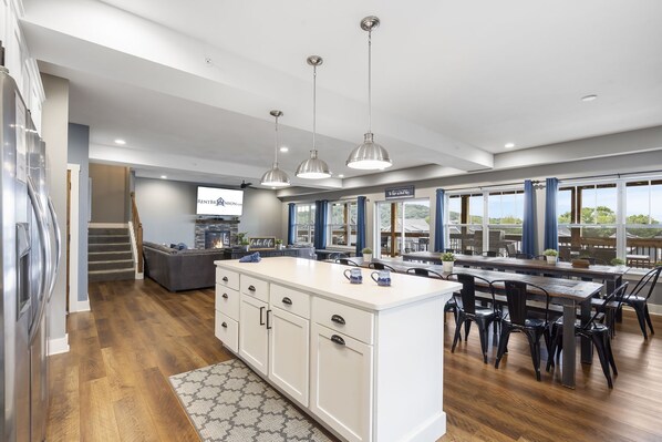 A modern kitchen with a central island, wooden flooring, and pendant lighting.