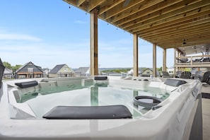A hot tub with a wooden deck and a view of houses in the background.