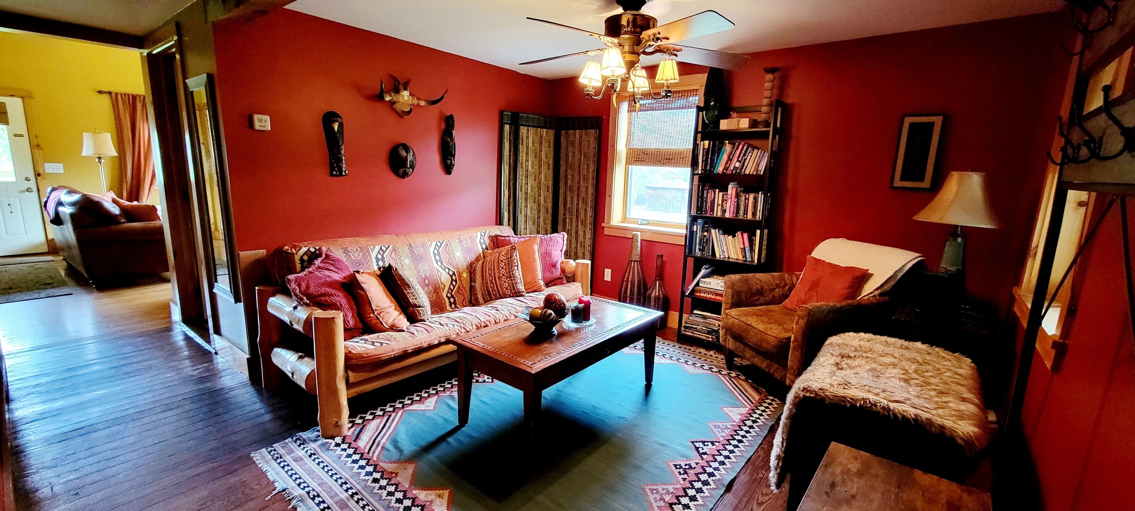 A living room with a red wall, a sofa, a coffee table, and a bookshelf.