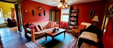 A living room with a red wall, a sofa, a coffee table, and a bookshelf.