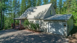 A single-story cabin with a covered porch, a garage, and a gravel driveway. - Scenic House Located At The Doorstep to West Glacier National Park Entrance
 (West Glacier)