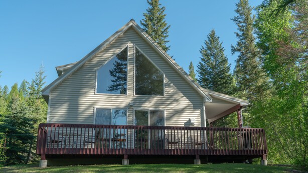 A two-story house with a deck, surrounded by trees. - Scenic House Located At The Doorstep to West Glacier National Park Entrance
 (West Glacier)