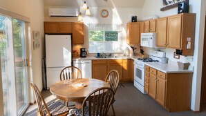 A kitchen with wooden cabinets, a refrigerator, a stove, and a dining table with chairs. - Scenic House Located At The Doorstep to West Glacier National Park Entrance
 (West Glacier)