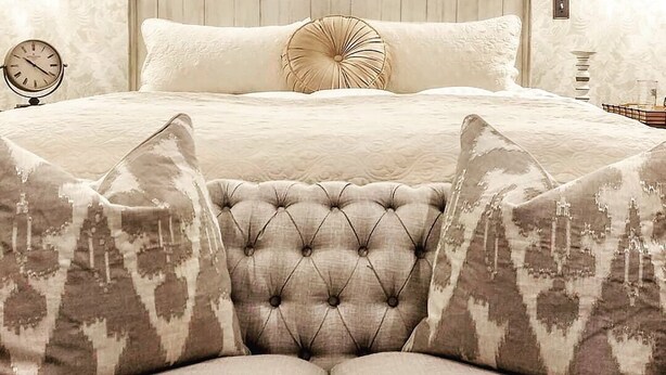 A bedroom with a large bed, a wooden headboard, and patterned pillows. - Historic, Elegant, Luxurious. (Mechanicsville)