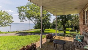 A covered patio with outdoor seating, a view of a lake, and a brick building. - Historic, Elegant, Luxurious. (Mechanicsville)