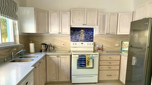 A kitchen with light wood cabinets, a white stove, a stainless steel refrigerator, and a tiled backsplash. - Beachfront Apartment in Paradise: Turtles Nest D (Dover)