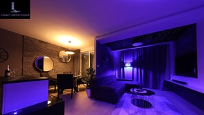 Ein modernes Wohnzimmer mit Steinwand, rundem Spiegel, Sofa und Fernseher.