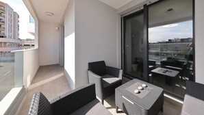 Ein Balkon mit Korbmöbeln, einer Glastür und Blick auf die Stadtlandschaft.