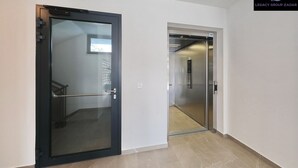 Ein moderner Flur mit Glastür und einer Metall-Aufzugstür.