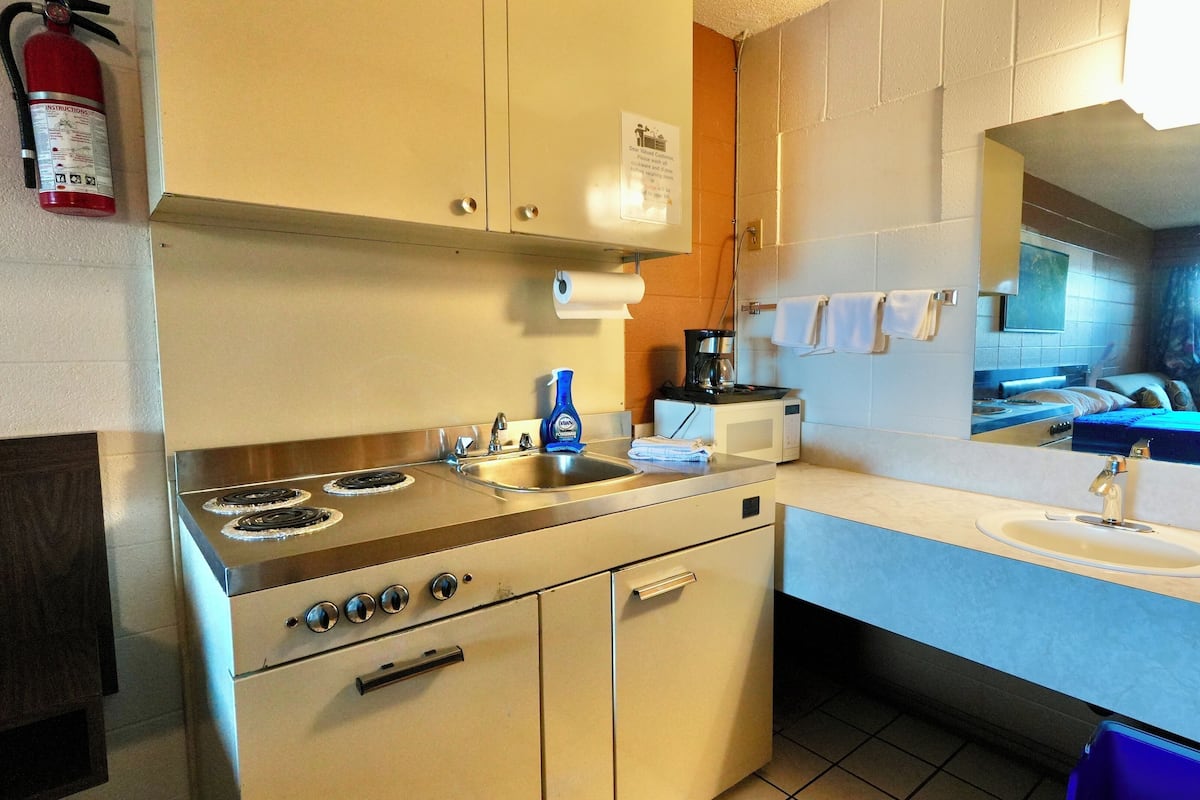 Una kitchenette compacta con estufa, pileta y cafetera.