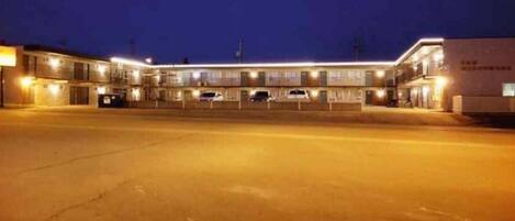 Un motel comprenant plusieurs chambres, un parking et un bâtiment sur lequel est apposée une enseigne indiquant « Motel ».