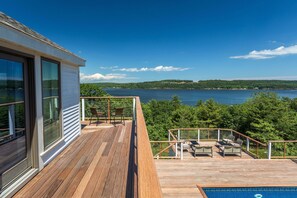 Une terrasse en bois, agréée de mobilier d’extérieur, donnant sur un lac.