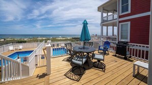 A wooden deck with a pool, outdoor furniture, and a view of the ocean. - Ocean Oasis by Carolina Getaway - Oceanfront Townhome w/ Private Heated Pool (Kure Beach)