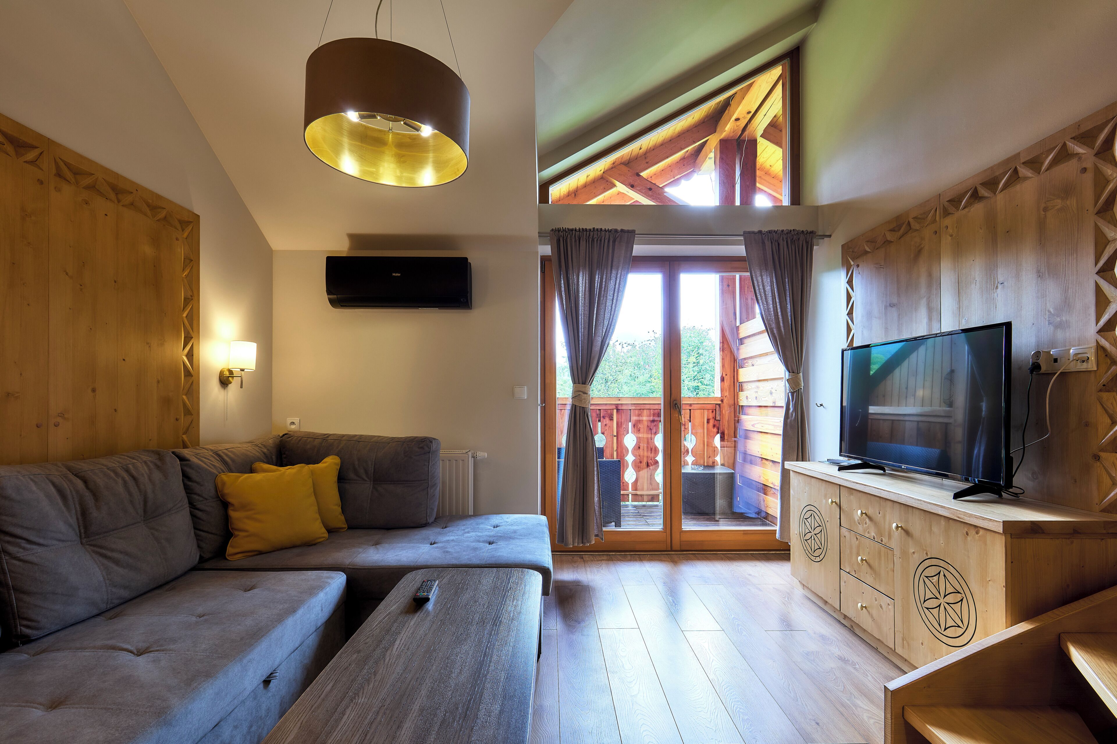 A living room with a sofa, TV, wooden cabinet, and a ceiling light.