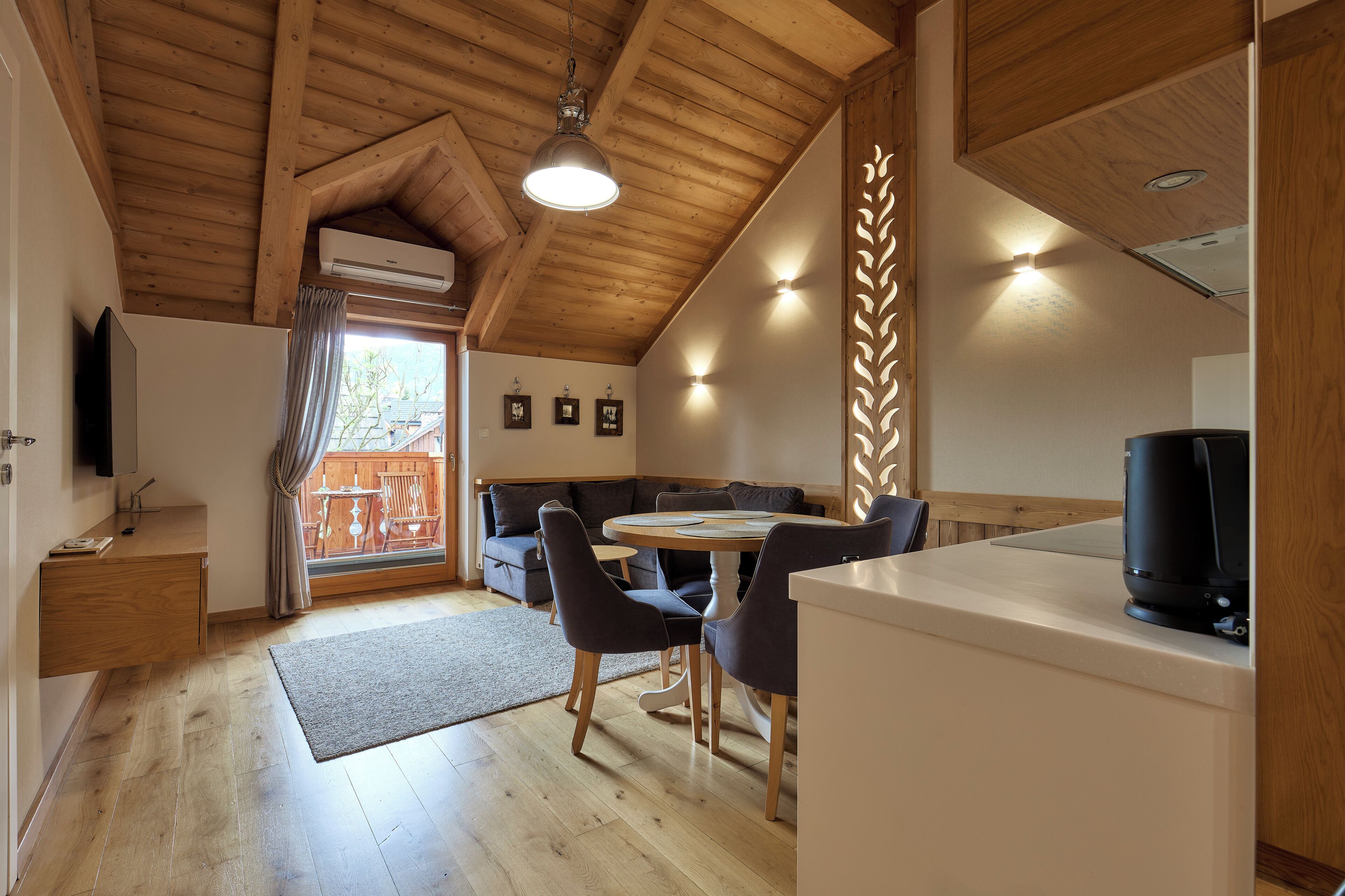 A wooden interior with a dining area, sofa, and a TV.