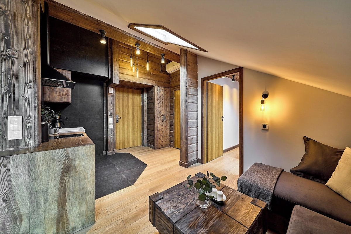 A modern interior with a wooden accent wall, a kitchen area, and a seating area with a coffee table.