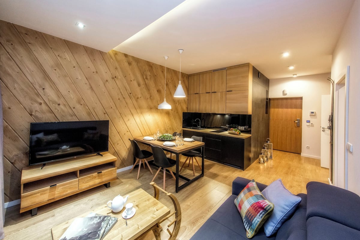 A modern living room with a TV, wooden furniture, a dining table, and a sofa.