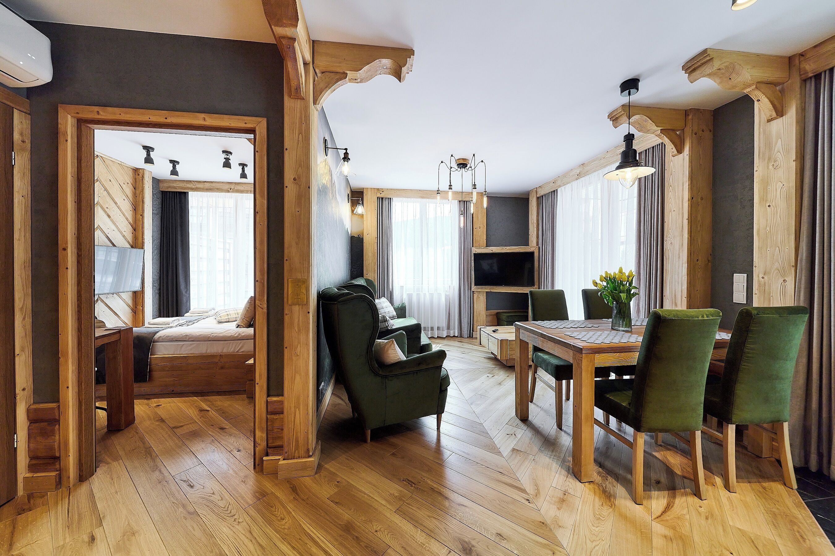 Ein geräumiger Wohnbereich mit Holzboden, einem Esstisch mit Stühlen, einer Couch und einem Fernseher.