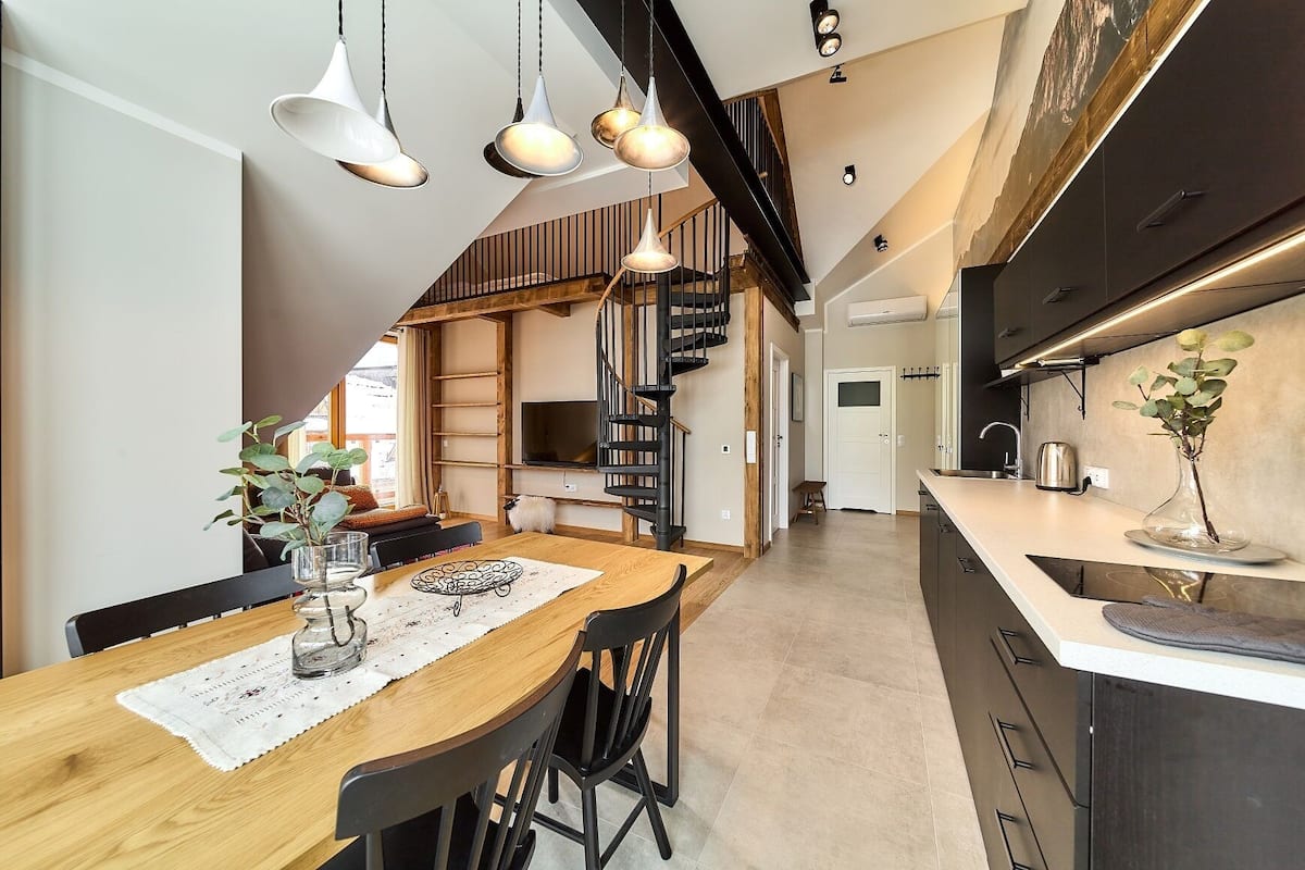 A modern kitchen with dark cabinets, a white countertop, and a hanging light fixture.