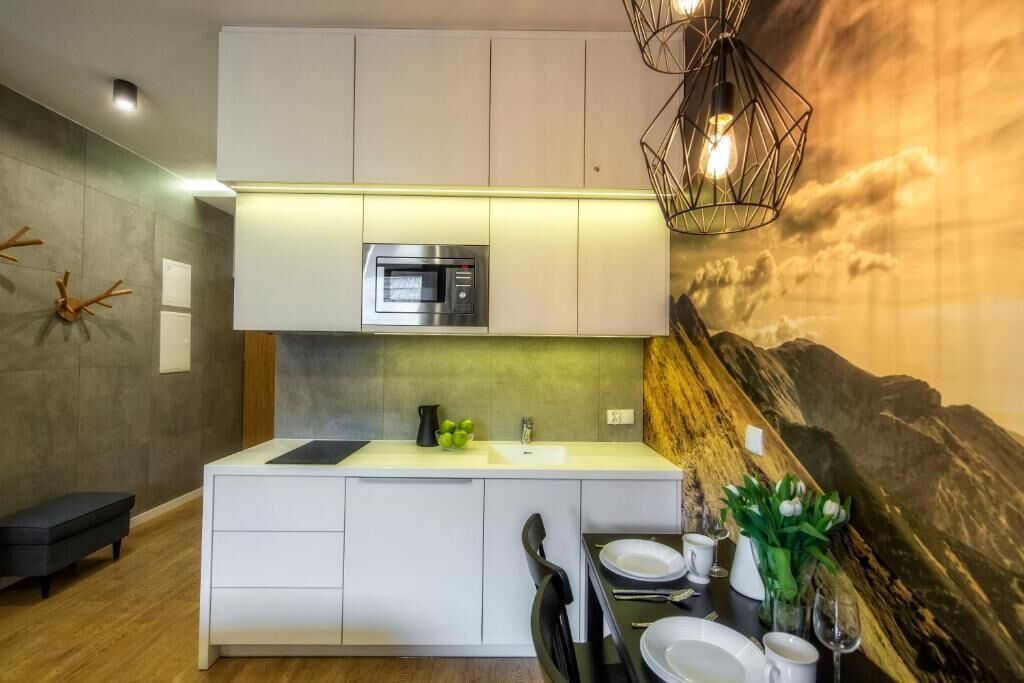 Eine moderne Küche mit integriertem Mikrowellenherd, Spüle und Essbereich mit Tisch für zwei Personen.