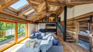 Un salón espacioso con un sofá grande, chimenea y vistas al exterior.