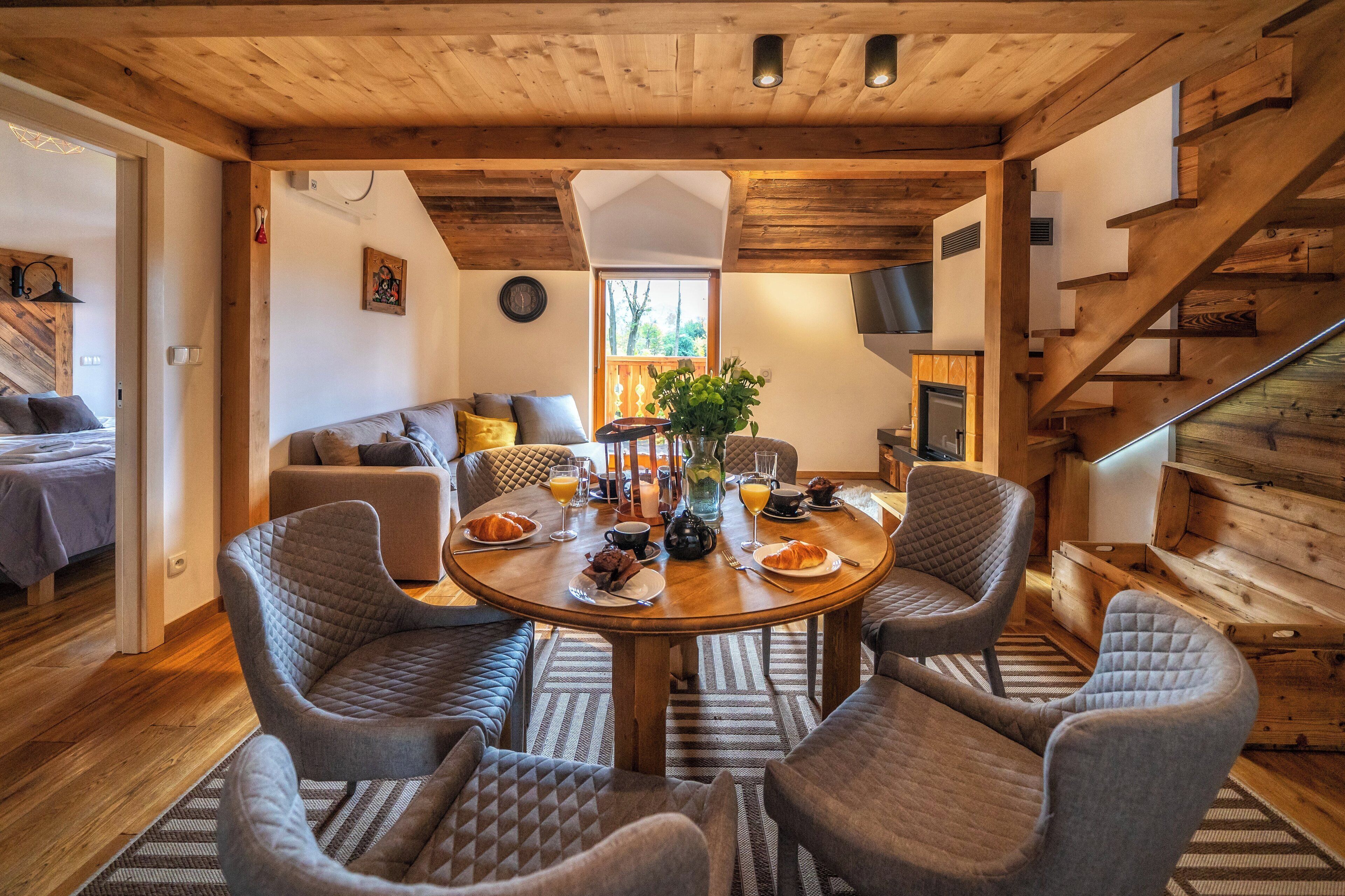 A cozy dining area with a wooden table, four upholstered chairs, and a vase with flowers.