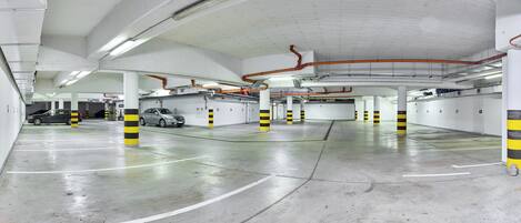 A multi-level parking garage with clearly marked parking spaces and striped safety bollards.