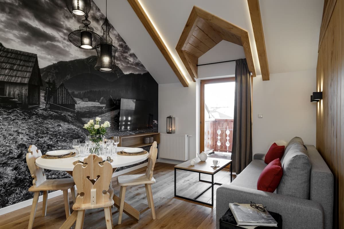 A modern living room with a dining area, featuring a wooden ceiling, a large mural, and a cozy seating arrangement.