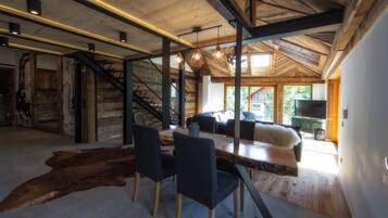 A spacious room with a wooden dining table, chairs, and a large window.