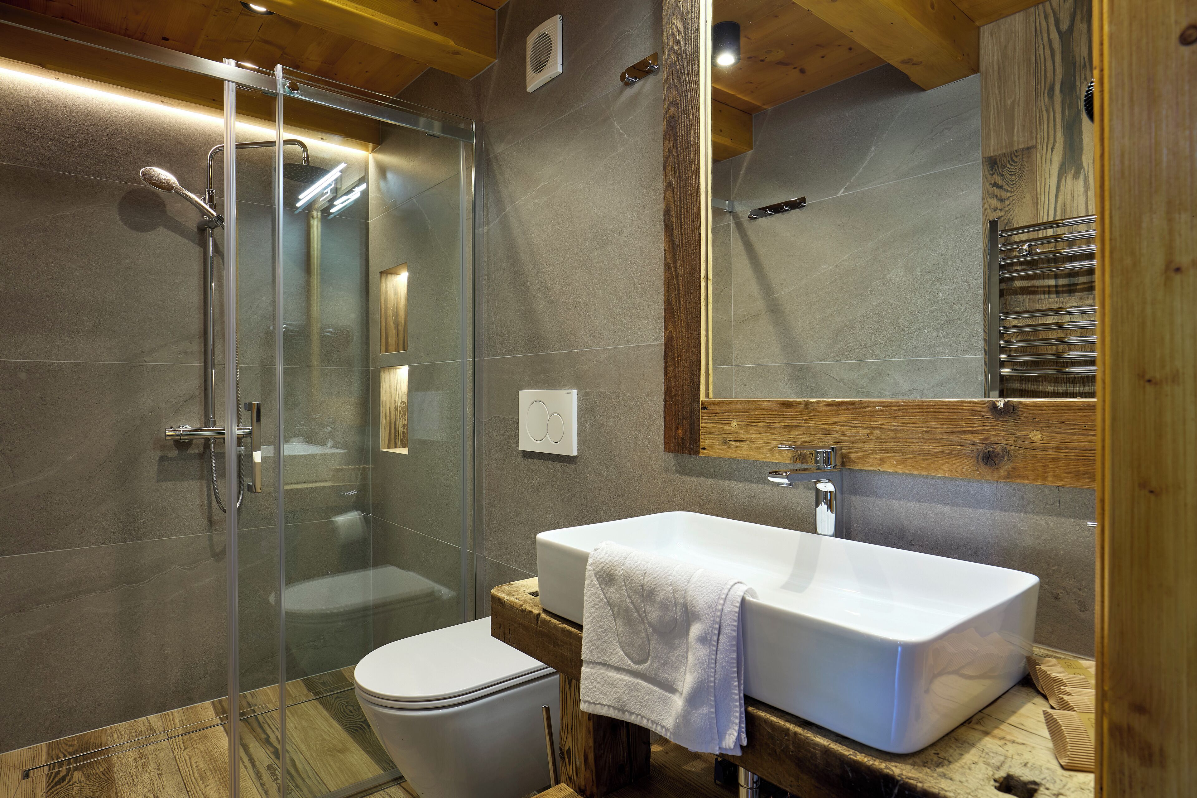 A modern bathroom with a glass-enclosed shower, a white sink, and a wooden vanity.