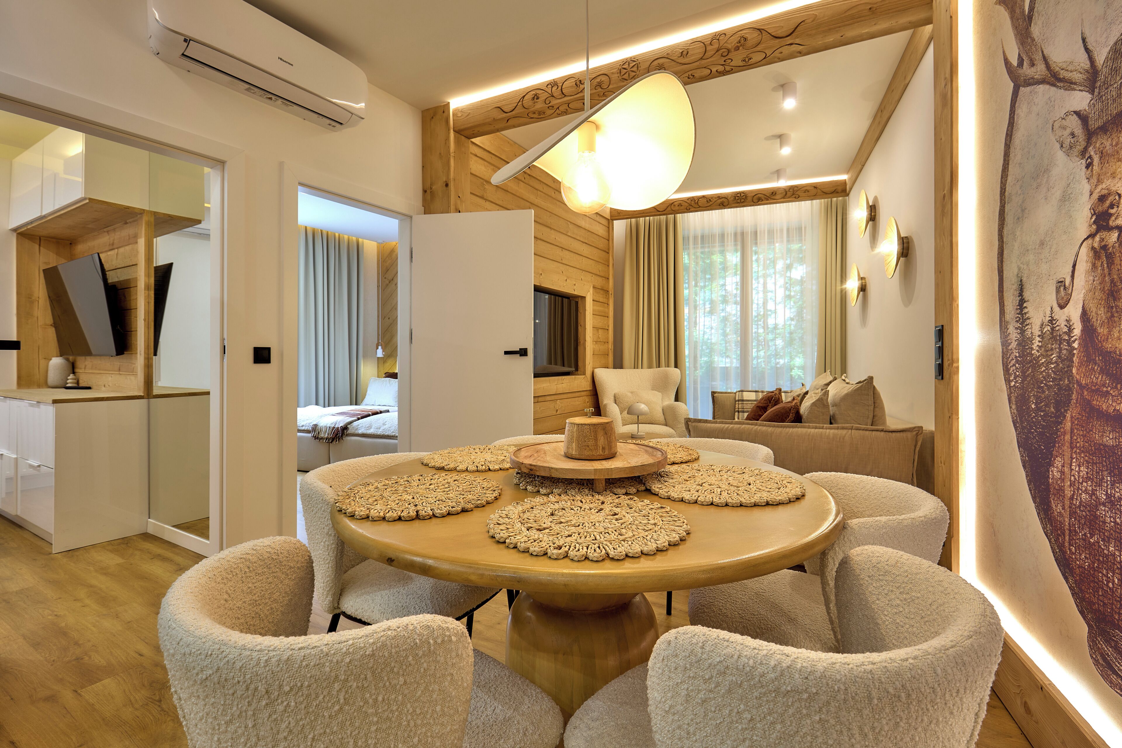 Un intérieur moderne avec une table ronde en bois entourée de chaises, d’un canapé et d’un grand tableau accroché au mur.