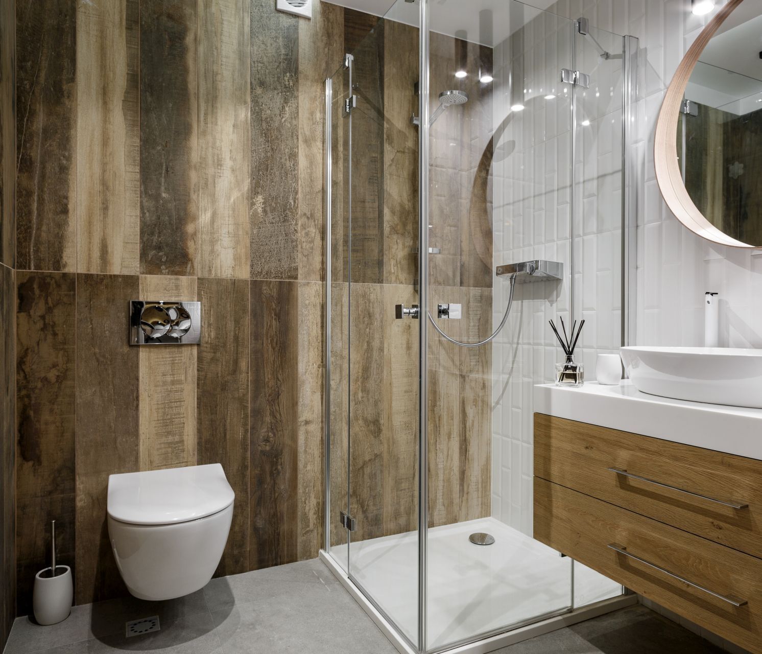 A modern bathroom with a glass-enclosed shower, a white toilet, and a wooden vanity with a mirror.