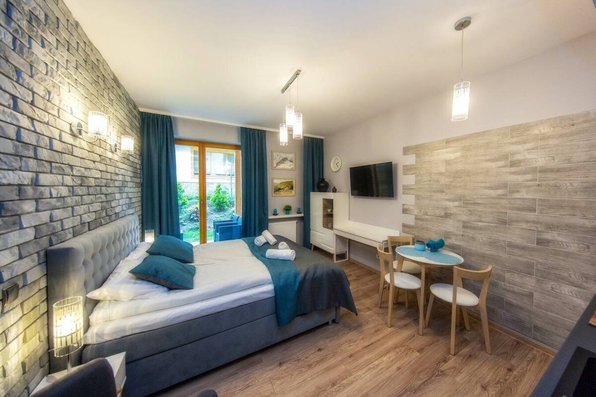 A modern hotel room with a large bed, a desk, and a dining area.