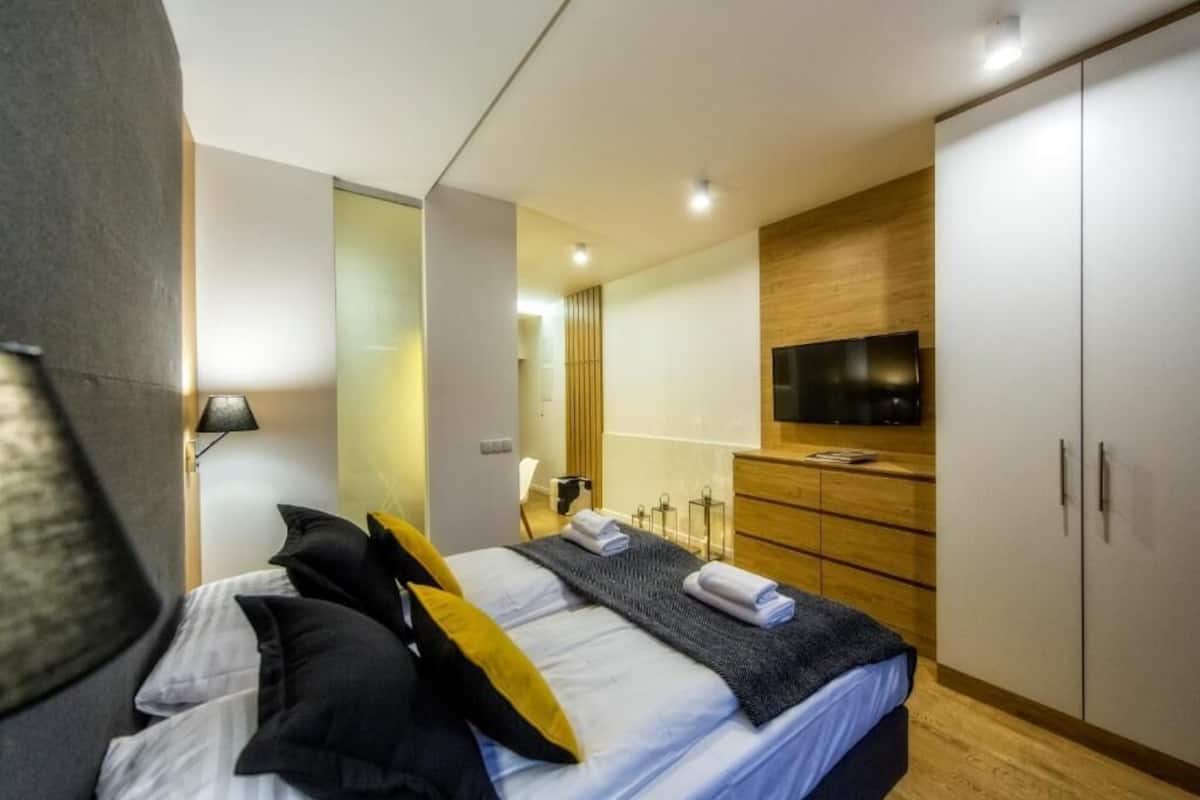 A modern hotel room with a bed, a TV, a wardrobe, and a mirror.