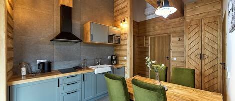 Una cocina moderna con armarios de madera, un lavamanos y un comedor con mesa de madera y sillas verdes.