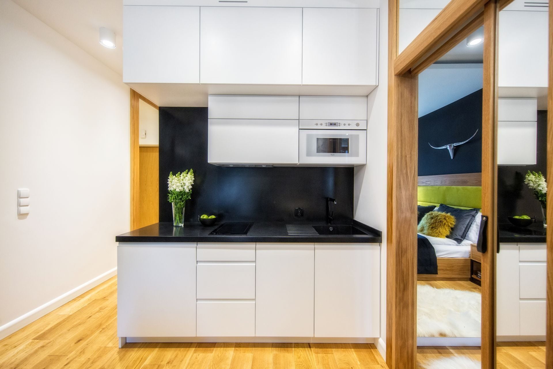 Una cocina moderna con armarios blancos, encimera negra y horno empotrado.