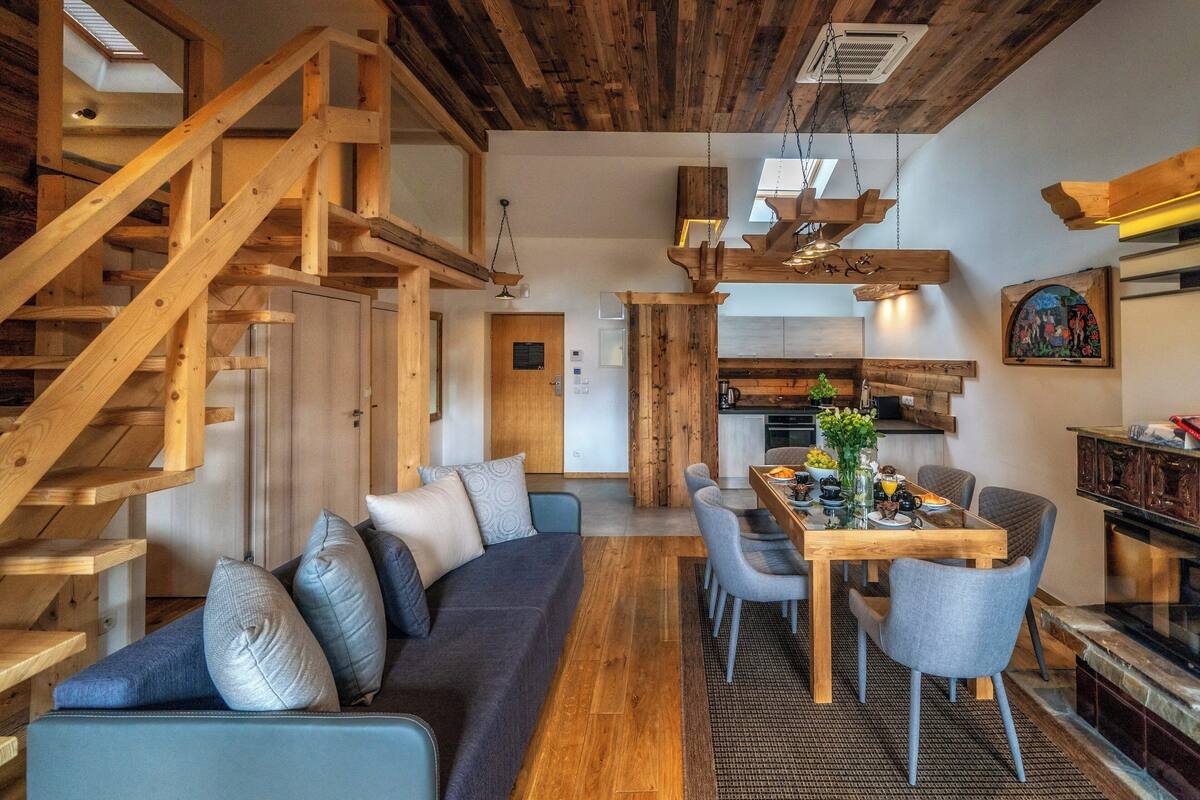 A modern interior with a wooden staircase, a dining area, and a kitchen.