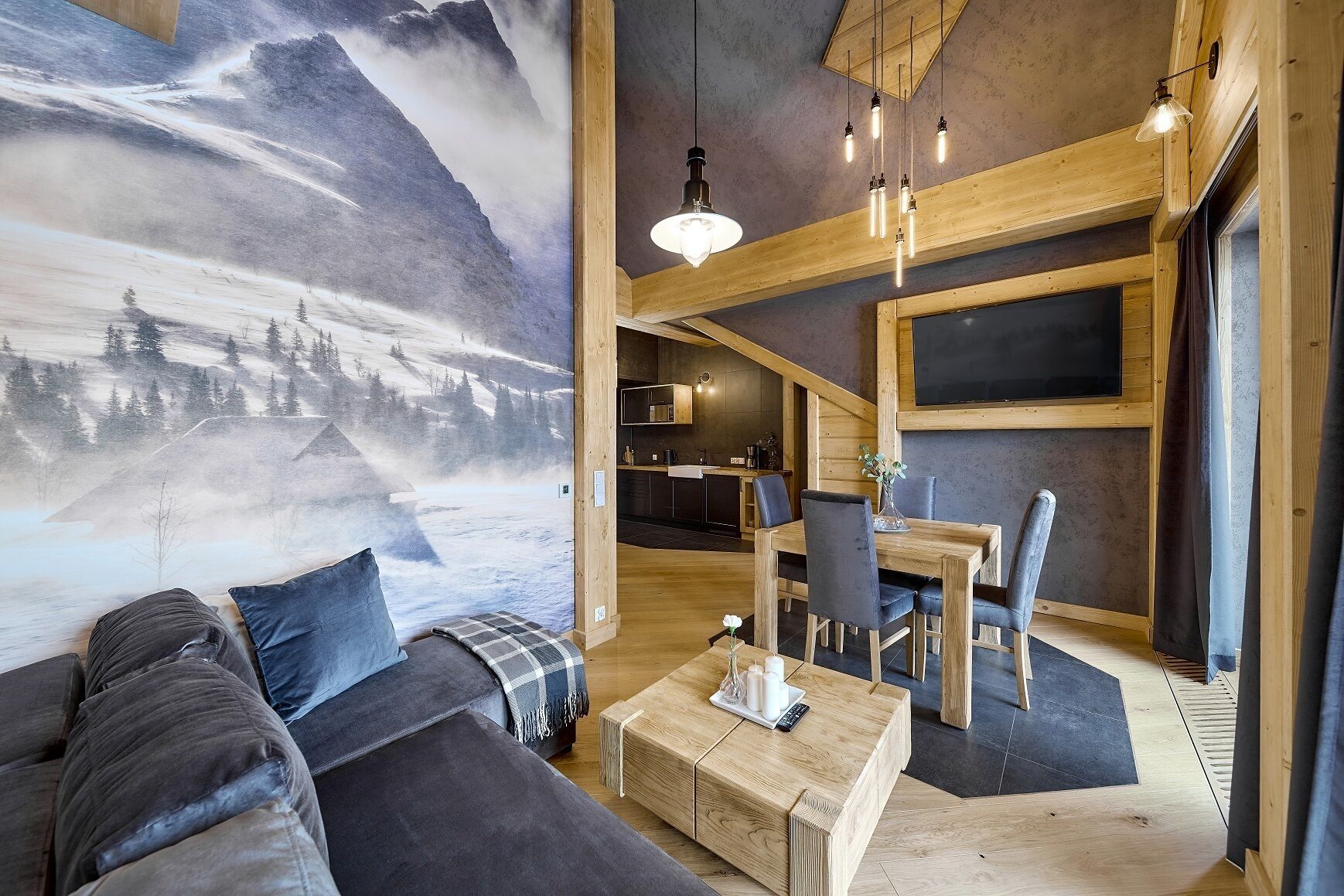 A cozy living area with a large mountain mural, wooden furniture, and a dining table with chairs.