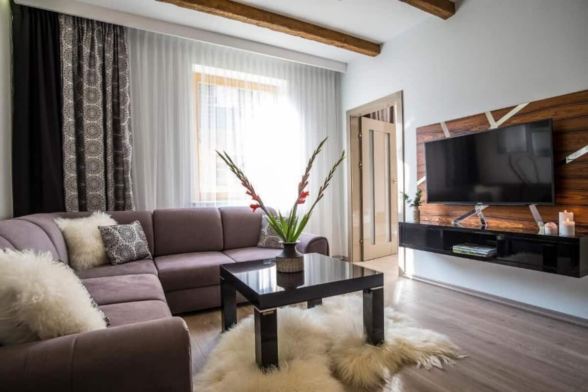 A modern living room with a sofa, a glass coffee table, and a mounted TV.